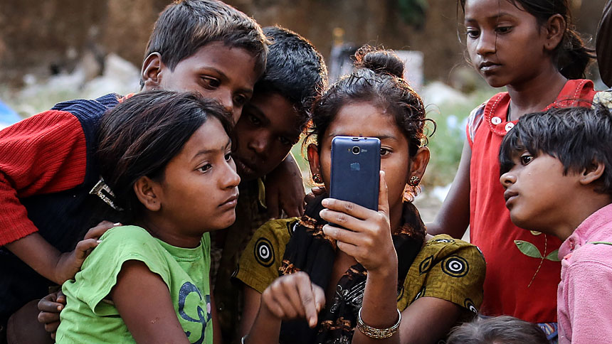 Indian children watch a movie on a cellphone on the roadside in Mumbai Jan. 20, 2016. While digital communications and social media can be used as a tool of evangelization and a place of dialogue with others, they also can be lonely environments where young people fall prey to humanity's worst vices, Pope Francis wrote in his new apostolic exhortation to young people, "Christus Vivit" ("Christ Lives"). (CNS photo/Divyakant Solanki, EPA)