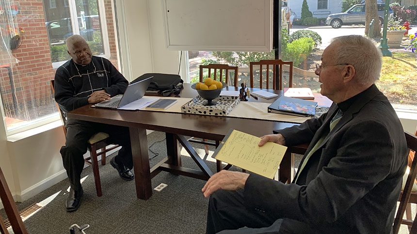 Father Joe Kakooza (left) discusses his school lunch program in Uganda with Monsignor Michael Shugrue.